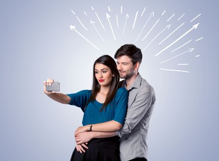 A cheerful young couple taking selfie photo with mobile phone and white lines and arrows pointing to the sky above them concept