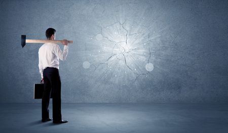 Business man hitting grungy wall with a hammer