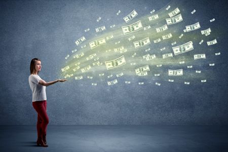 Caucasian woman holding money, which flies from her hands