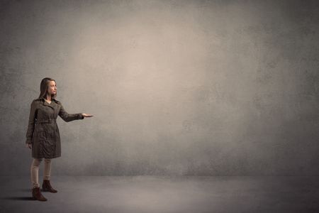 Caucasian woman standing in front of a blank grunge wall