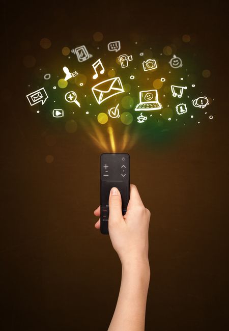 Hand holding a remote control, social media icons coming out of it