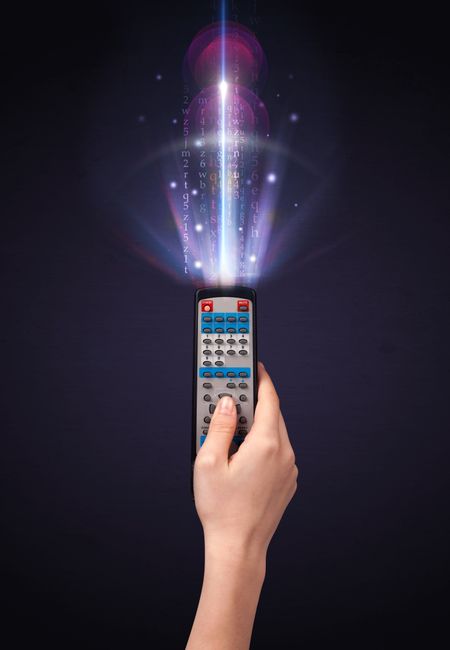 Hand holding a remote control, shining numbers and letters coming out of it