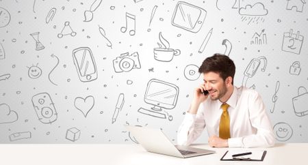 Businessman sitting at table with hand drawn media icons and symbols 