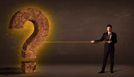 Business man pulling a big solid question mark stone concept on background