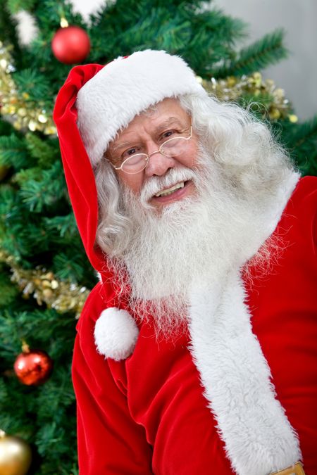 Happy Santa next to a Christmas tree smiling