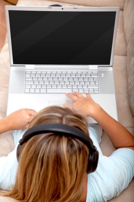 woman with headphones and a laptop downloading music