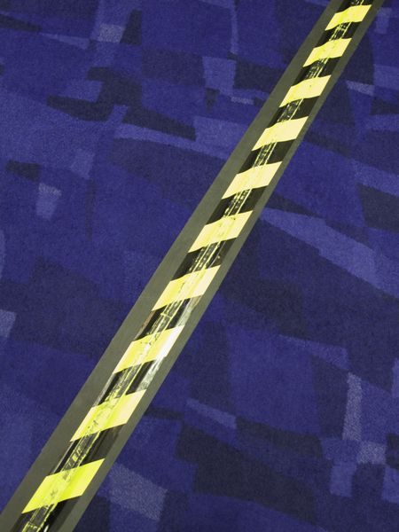 Striped safety tape over electrical cord across carpet in convention center