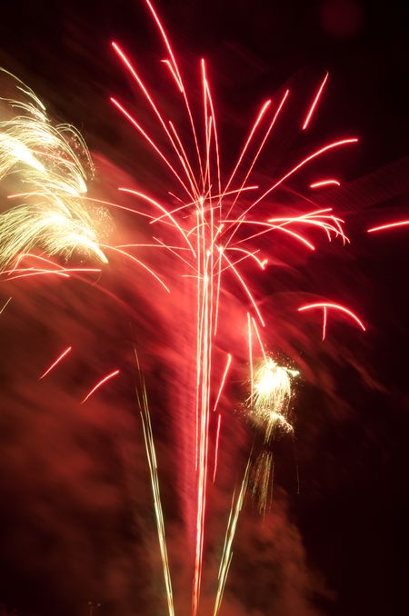 Bright bursts of low-altitude fireworks in reddish smoke
