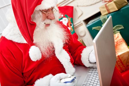 Happy Santa Claus working on a laptop