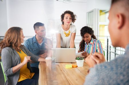 Multi ethnic group of succesful creative business people using a laptop during candid meeting