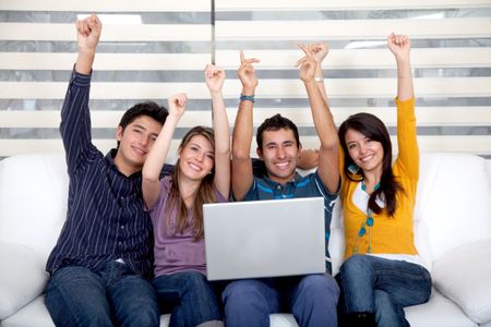 Excited group of people sitting on the sofa with a laptop