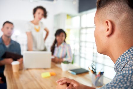 Multi ethnic group of succesful creative business people using a laptop during candid meeting