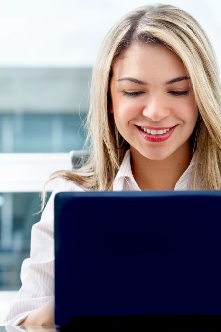 business woman looking happy on a laptop in her office
