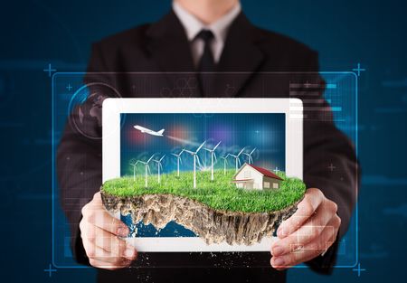 Young businessman presenting a perfect ecology land with a house and windmills