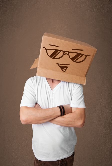 Young man standing and gesturing with a cardboard box on his head with smiley face