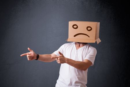 Young man standing with a brown cardboard box on his head with sad face
