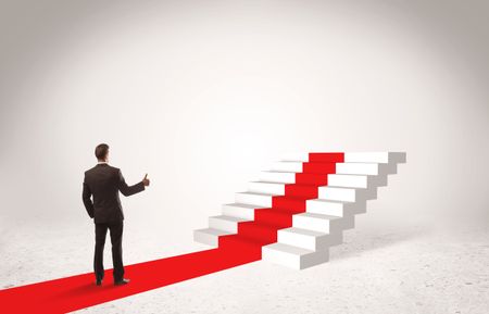 A successful businessman with briefcase standing on red carpet in front of steps in white space concept