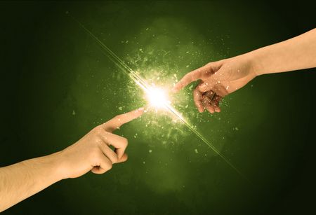 Two naked male hands about to touch, lighting the spark with modest explosion in front of green background concept