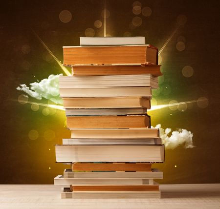 Magical books with ray of lights and colorful clouds on vintage background