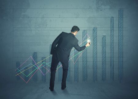 Young businessman drawing chart on wall