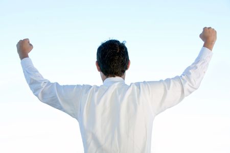 business man standing with his arms up representing his success from back - isolated over a white background