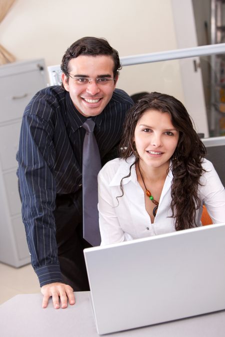 business couple smiling on a laptop in an office