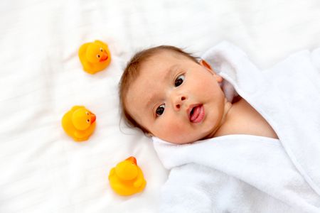beautiful baby boy portrait lying on bed with yellow rubber ducks