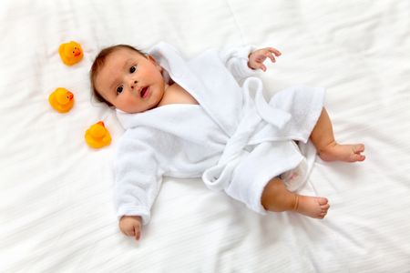 Cute baby lying on a bed with ducks toys