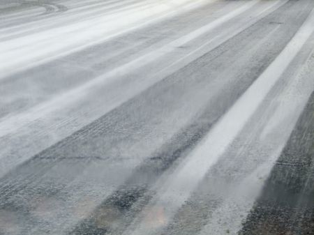 Icy street seen through streaked windshield of car