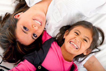 Mother and daughter smiling isolated over a white background