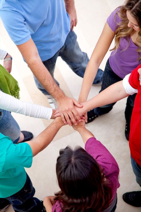 Casual group of friends with hands in the middle indoors