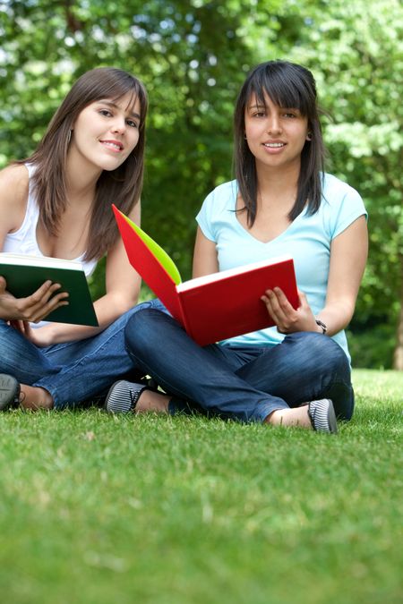 Beautiful happy students with books at the park