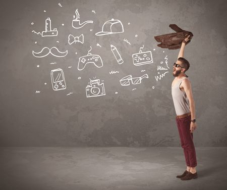 A funny hipster person in casual urban clothing shouting drawn everyday items like camera, tie or pen on city wall concept