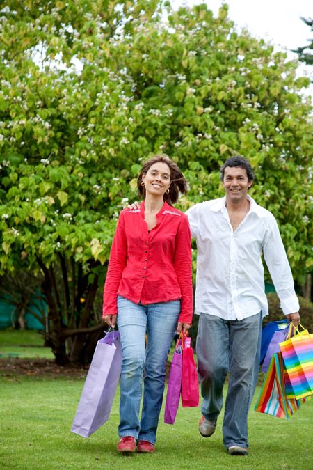 Happy couple of shoppers outdoors with shopping bags