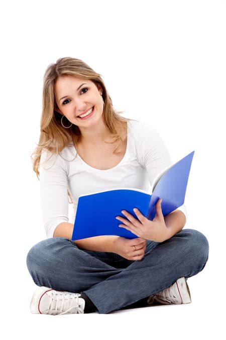 Beautiful happy female student sitting on the floor with a notebook isolated on white