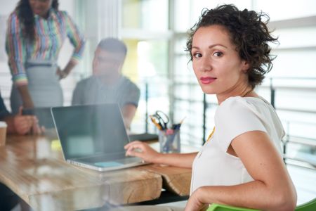 Image of a succesful casual business woman using laptop during meeting