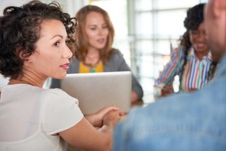 Multi ethnic group of succesful creative business people using a laptop during candid meeting