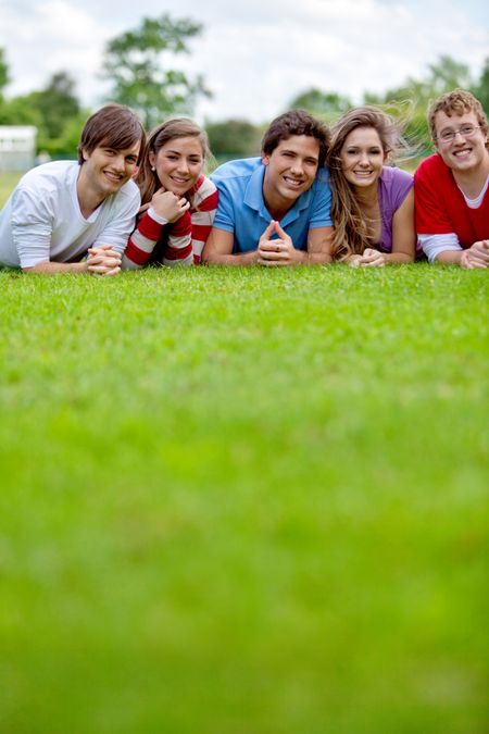 Happy group of friends lying on grass outdoors