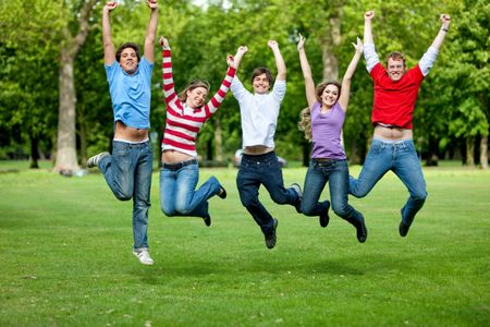 Group of friends jumping outdoors and smiling