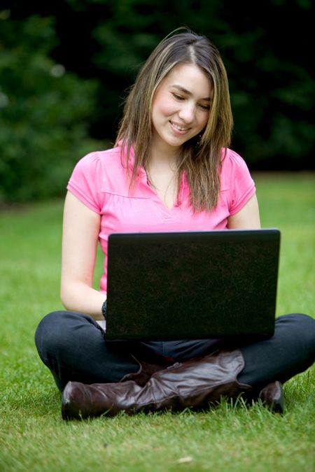 Casual woman with a laptop outdoors and smiling