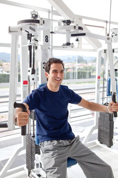 Happy man at the gym exercising on a machine