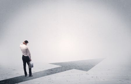 A professional businessman thinking while standing on a black arrow pointing forward in grey space concept