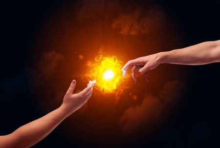 Two naked male hands about to touch, lighting a bright flame with smoke in red sky background concept