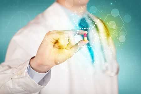 male-doctor-white-coat-stethoscope-holding-453573943 A male doctor in white coat with a stethoscope holding a pill with glowing colorful dots and lines
