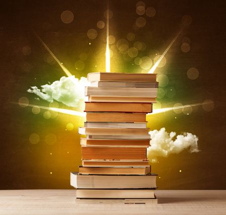 Magical books with ray of lights and colorful clouds on vintage background