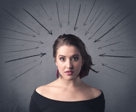 A teenage student girl under pressure while making happy face expressions illustrated with black arrows pointing at her head on the wall blackground concept.