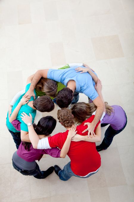 Team people hugging making a circle together indoors