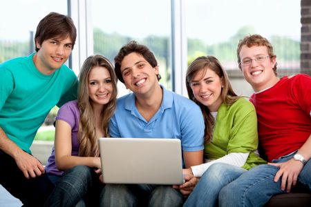 Happy group of friends together browsing on the computer indoors