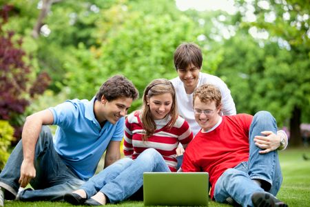 Happy group of friends outdoors with a laptop