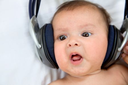 Cute baby with headphones listening to music